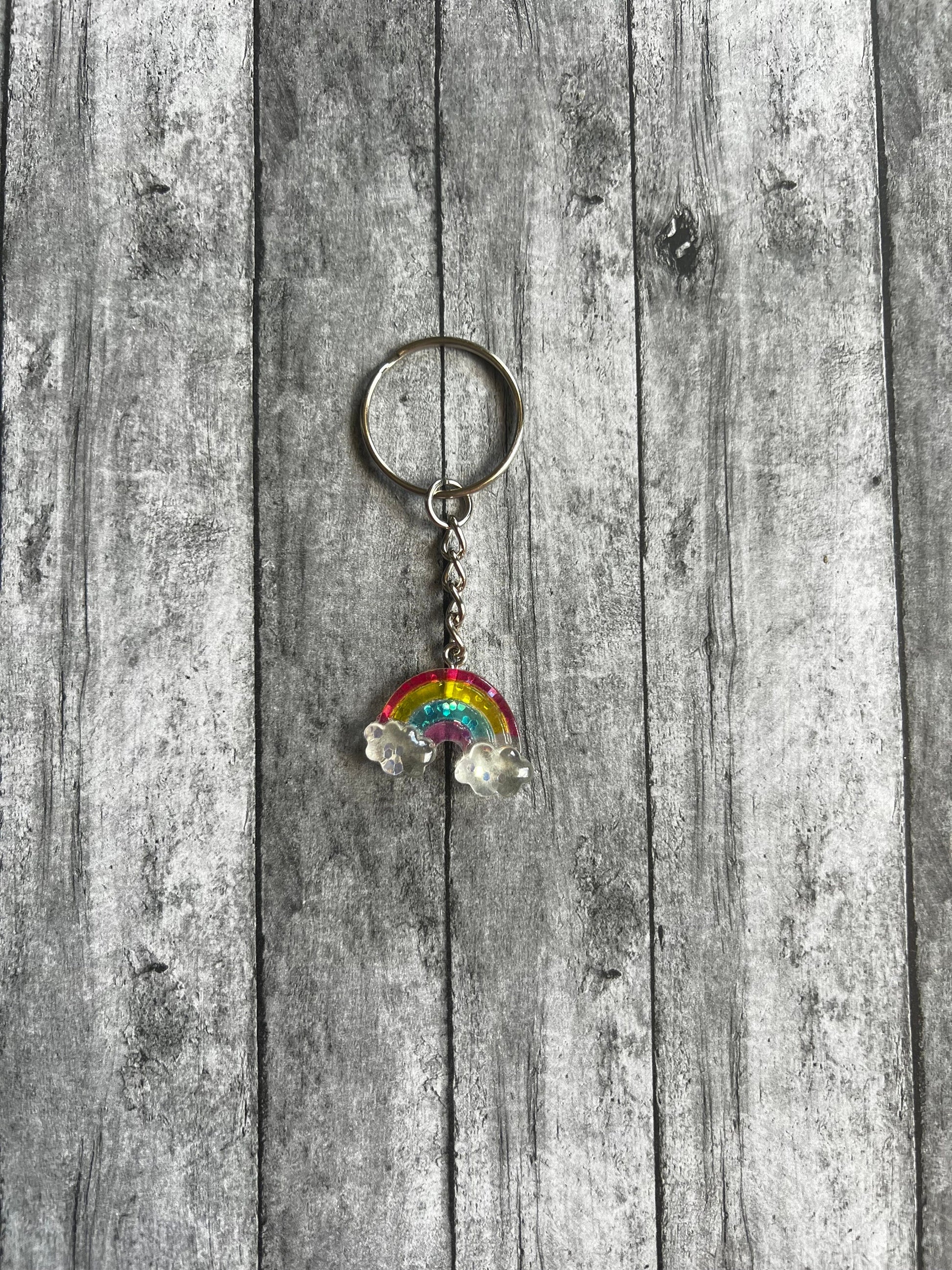 Rainbow has several beautiful colors it first has these colors in order red, yellow, light blue, and dark pink. There is glitter throughout pendant. At each end of rainbow it has clear clouds with glitter.